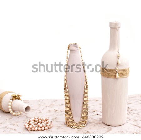 Bottle for home decoration on textured background. Paint, decor twine. Necklace, bracelet.
