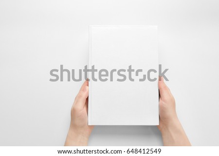 Female hands holding closed book with blank cover on light background Royalty-Free Stock Photo #648412549
