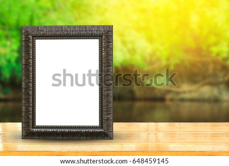Vintage picture frame on wooden table with nature blurred background use for texts display
