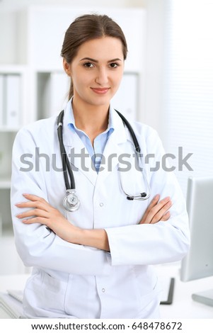 Latin american doctor woman standing with arms crossed and smiling at hospital. Physician ready to examine patient