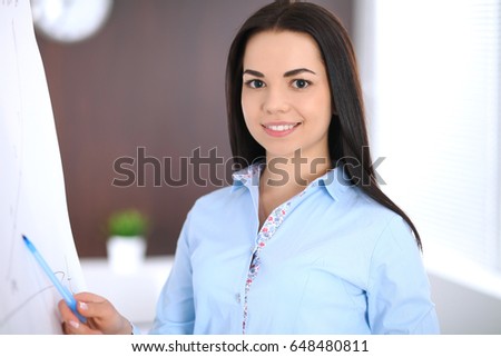 Young business woman or student-girl standing with crossed arms  in office. Blue colored bluse. Education or business concept