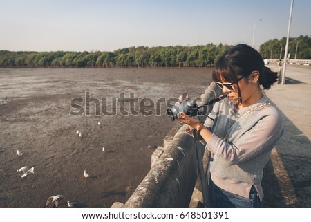Beautiful asian woman talking picture of seascape and birds in Bang pu seaside, Thailand.