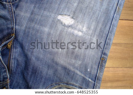 Light blue jeans and bit torn on a brown wooden background