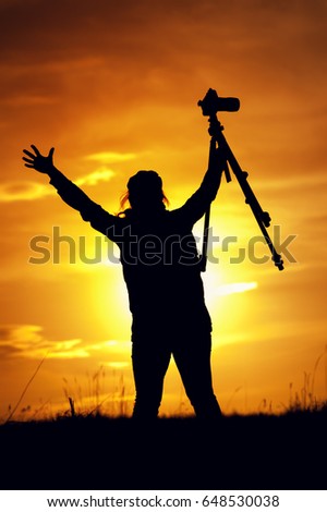Female photographer silhouette at setting sun