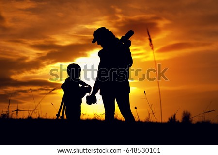 Silhouettes of mother photographer and little son