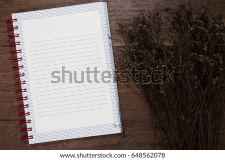Blank book and dry flower on old desk