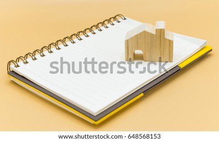 Wooden house model and Pencil on Notebook on white background, Plan to buy a house in the future or Family planning concept. copy space.