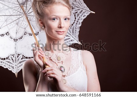 Portrait of woman in vintage dress holding a lace umbrella. Rich and vintage. Luxury and elegance. Studio photo