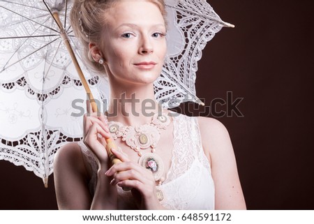 Portrait of woman in vintage dress holding a lace umbrella. Rich and vintage. Luxury and elegance. Studio photo
