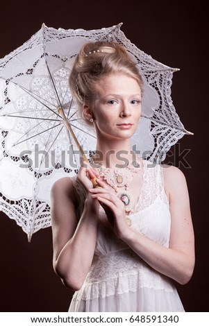 Woman in vintage dress holding a lace umbrella. Rich and vintage. Luxury and elegance. Studio photo