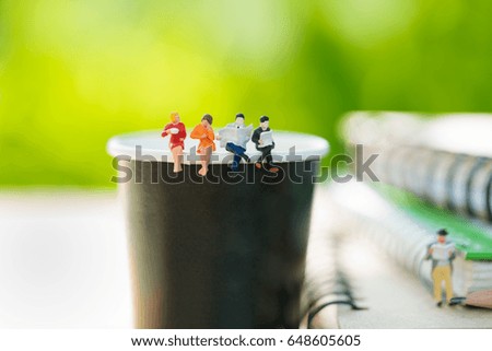 Miniatures people sitting on a cup of coffee using as background business concept.