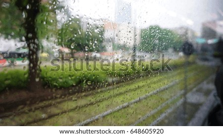 The rain drops on the glass with railway and city view blurred background, take this picture from the bus with the out of focus blurred technique