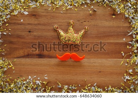 Top view image of funny red mustache and glitter crown on wooden background. Father's day concept