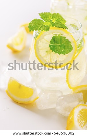Lemonade drink in a glass: water, ice, lemon slice and mint. Copy space