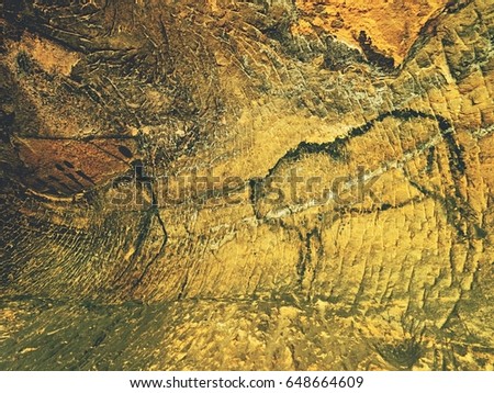 Buffalo hunting. Paint of human hunting on sandstone wall, prehistoric picture. Black carbon abstract children art in sandstone cave. Spotlight shines on prehistorical human painting.