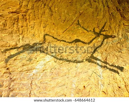 Black carbon paint of deer on sandstone wall, prehistorical picture. Abstract art in sandstone cave. Black carbon symbols of human hunting,  prehistoric picture. Discovery of human history