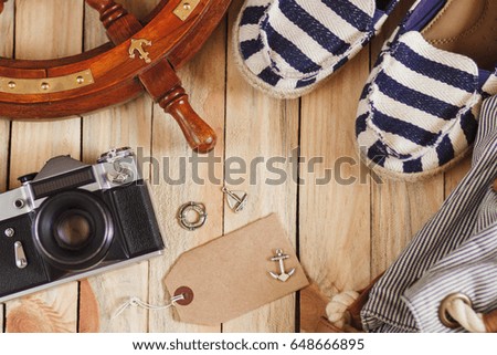 Striped slippers, camera, bag and maritime decorations on the wooden background, top view