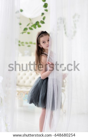 Sweet little dark hair girl in black skirt poses in studio