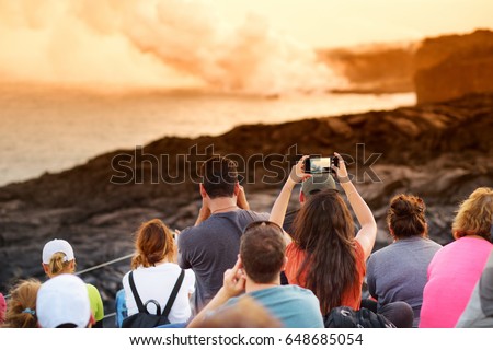 Tourists taking photos at Kalapana lava viewing area. Lava pouring into the ocean creating a huge poisonous plume of smoke at Hawaii's Kilauea Volcano, Volcanoes National Park, Big Island of Hawaii