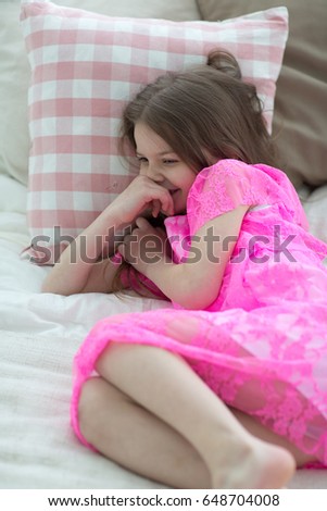 Pretty little girl in pink princess dress in bed with cushion