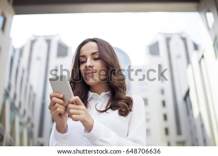 Attractive modern Young business woman enjoys a phone or writes a message on a business center background.