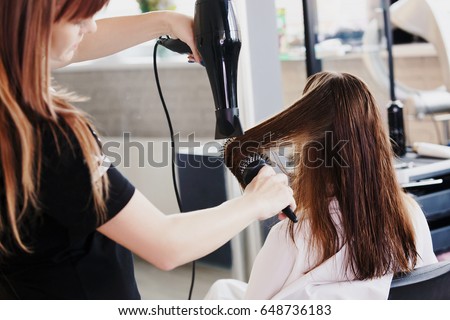 Hairdresser dries hair with a hairdryer in beauty salon Royalty-Free Stock Photo #648736183