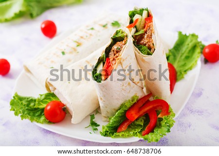 Burritos wraps with minced beef and vegetables on a light background. 