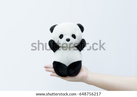 hand holding panda doll, black rim of eyes,panda toy on white background