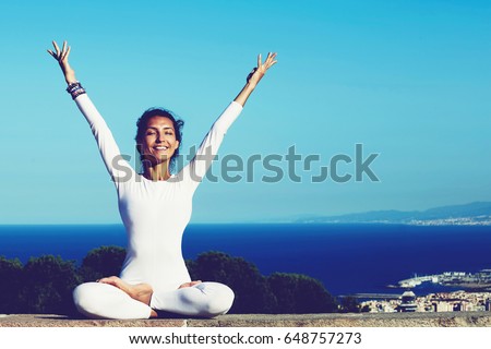Portrait of gorgeous smiling woman practicing yoga by raising her hands feeling so good and happy, young woman seeking enlightenment through meditation, relaxed girl performing yoga routine, filter