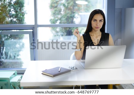 Confident attractive businesswoman making money transfer using online banking service using laptop computer, portrait of serious company owner doing remote job checking documentation in database