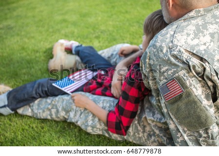 American soldier reunited with son on a sunny day, detail, focus on shoulder with american flag label