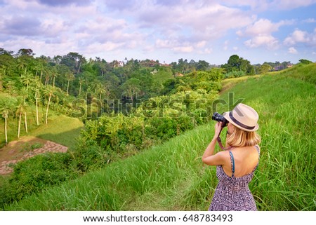 Traveling and photography. Young woman taking picture with her camera enjoying tropical landscape.