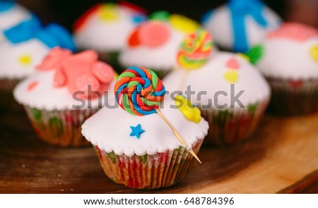 Baby cupcakes on the wooden background.