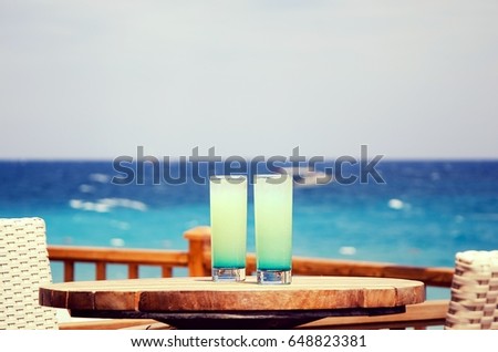 Two blue cocktails on the summer beach terrace of the restaurant on the background of the sea, the ocean Royalty-Free Stock Photo #648823381