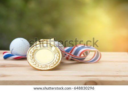 old gold medal and golf ball on wood in morning, soft background, Winner concept