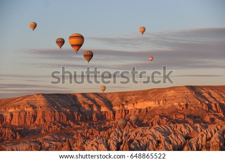 Hot air ballons flying over Cappadocia during sunset time in a sunny day with some clouds, during October, Turkey Royalty-Free Stock Photo #648865522