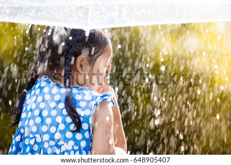Back view of two happy asian little girls with umbrella having fun to play with the rain together in vintage color tone