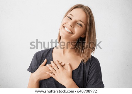 Beautiful positive friendly-looking young mixed race woman with lovely sincere smile feeling thankful and grateful, showing her heart filled with love and gratitude holding hands on her breast Royalty-Free Stock Photo #648908992