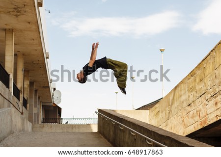 Young man back flip. Parkour in the urban space. Sport in the city. Sport Activities outdoors. Acrobatics Royalty-Free Stock Photo #648917863