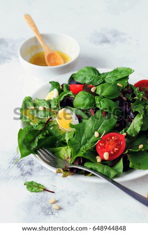 Fresh green salad with cherry tomatoes pine nuts and quail eggs. Salad dressing. Healthy eating. 