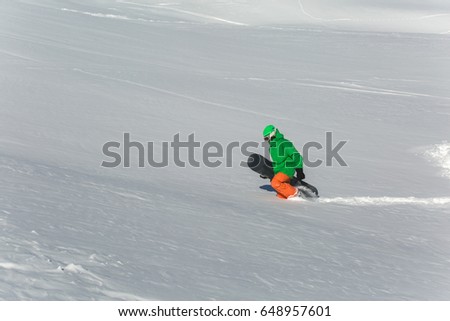 Male snowboarder snowboarding on fresh snow on ski slope on Sunny winter day in the ski resort in Georgia. Travel adventure concept. space for text