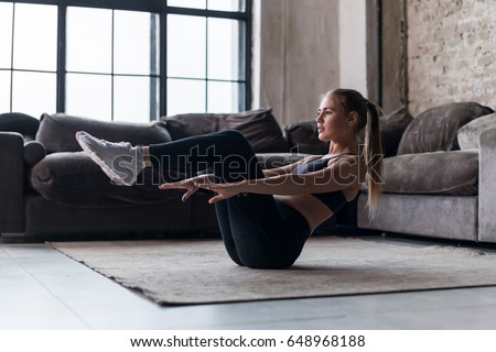 Slim sporty girl doing v-ups abs workout at home Royalty-Free Stock Photo #648968188
