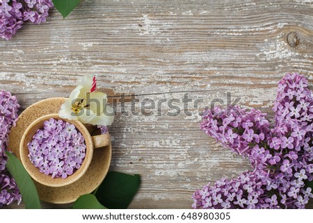 Beautiful cup of lilac flowers on an old textured board. Flat lay, top view.