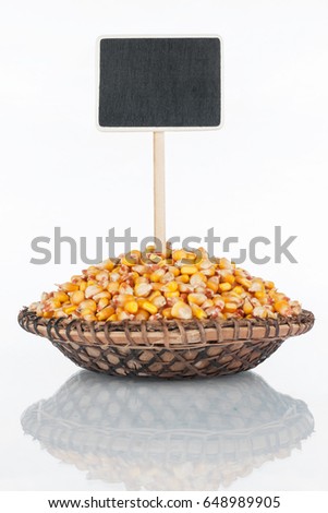 Plate with a bunch of corn grains and its reflection and price tag, pointer. With a place for your text