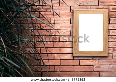 Mock up blank poster picture wooden frame on old brick wall in vintage tone with grass front ground.	