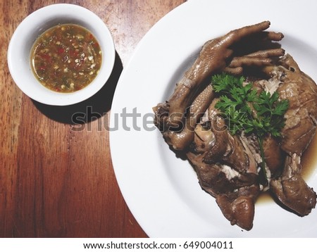 This is boiled chicken in fish sauce with spicy sauce above wooden table,  soft tone