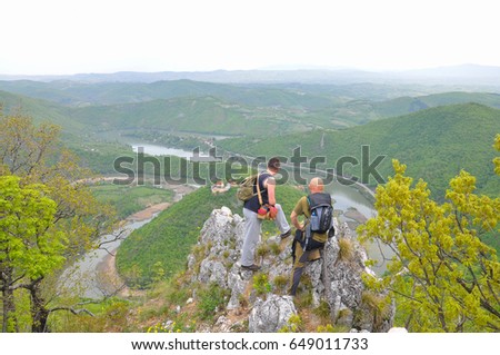 Hikers on top of a mountain enjoy the beautiful view of nature, forest and river in valley. View on meanders of Morava river  from Kablar, Serbia