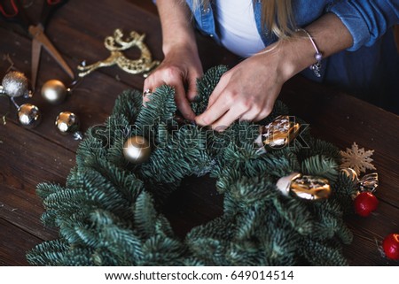 Decorator prepares christmas wreath with fir branches and toys