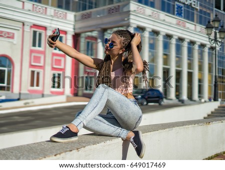 beautiful girl with zizi cornrows dreadlocks shooting selfie on her smartphone. Urban street style