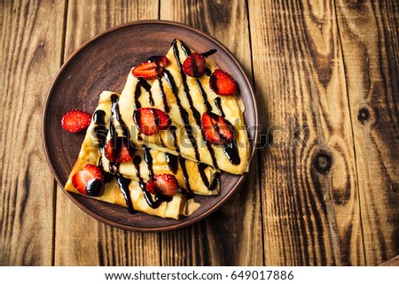 crepes pancakes on ceramic plate strawberry and chocolate Royalty-Free Stock Photo #649017886